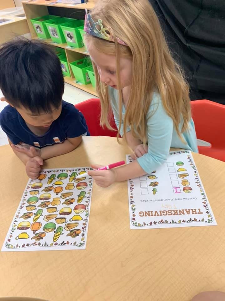 Two children at a table looking at papers with drawings
