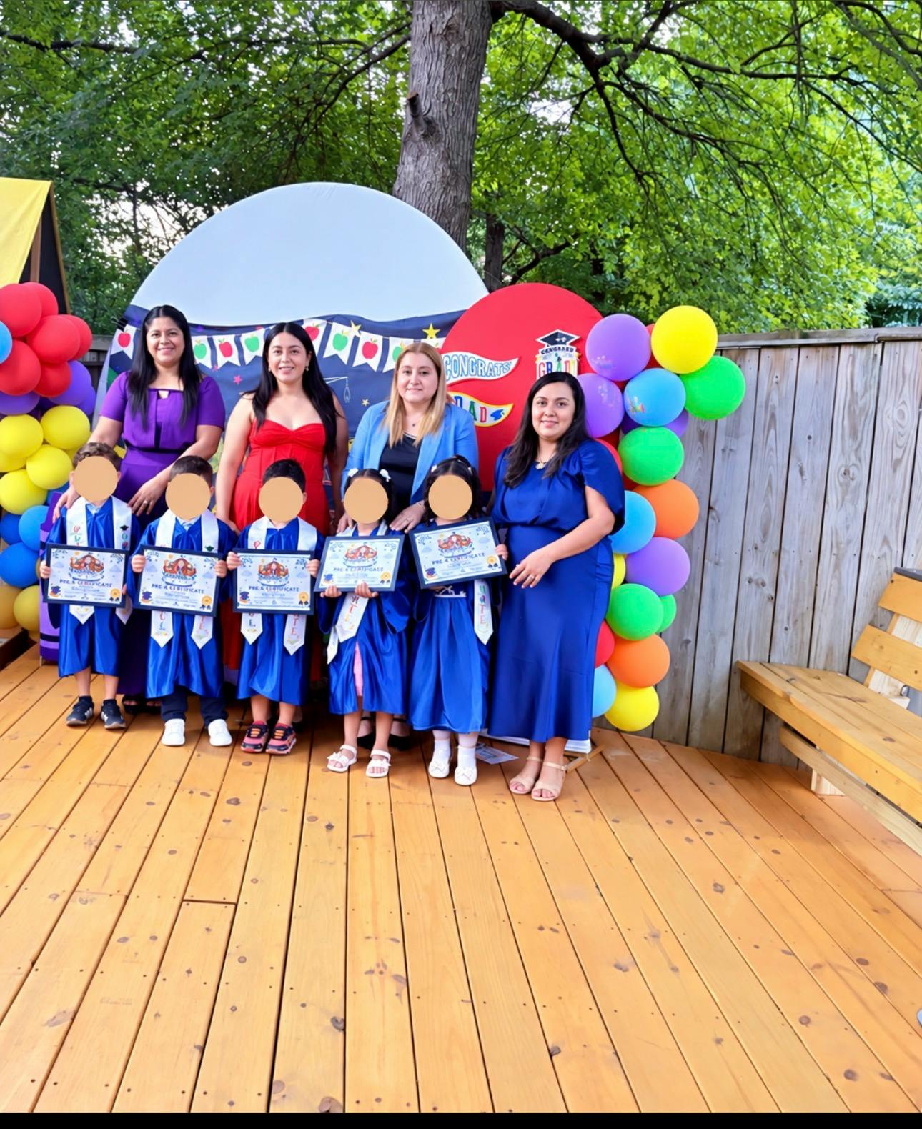 Group of adults and children in graduation caps holding certificates