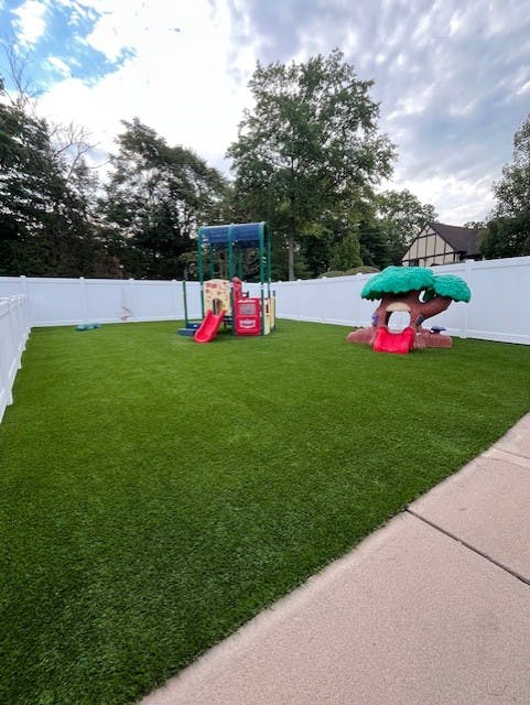 Backyard with artificial turf, a playset, and a tree-shaped slide