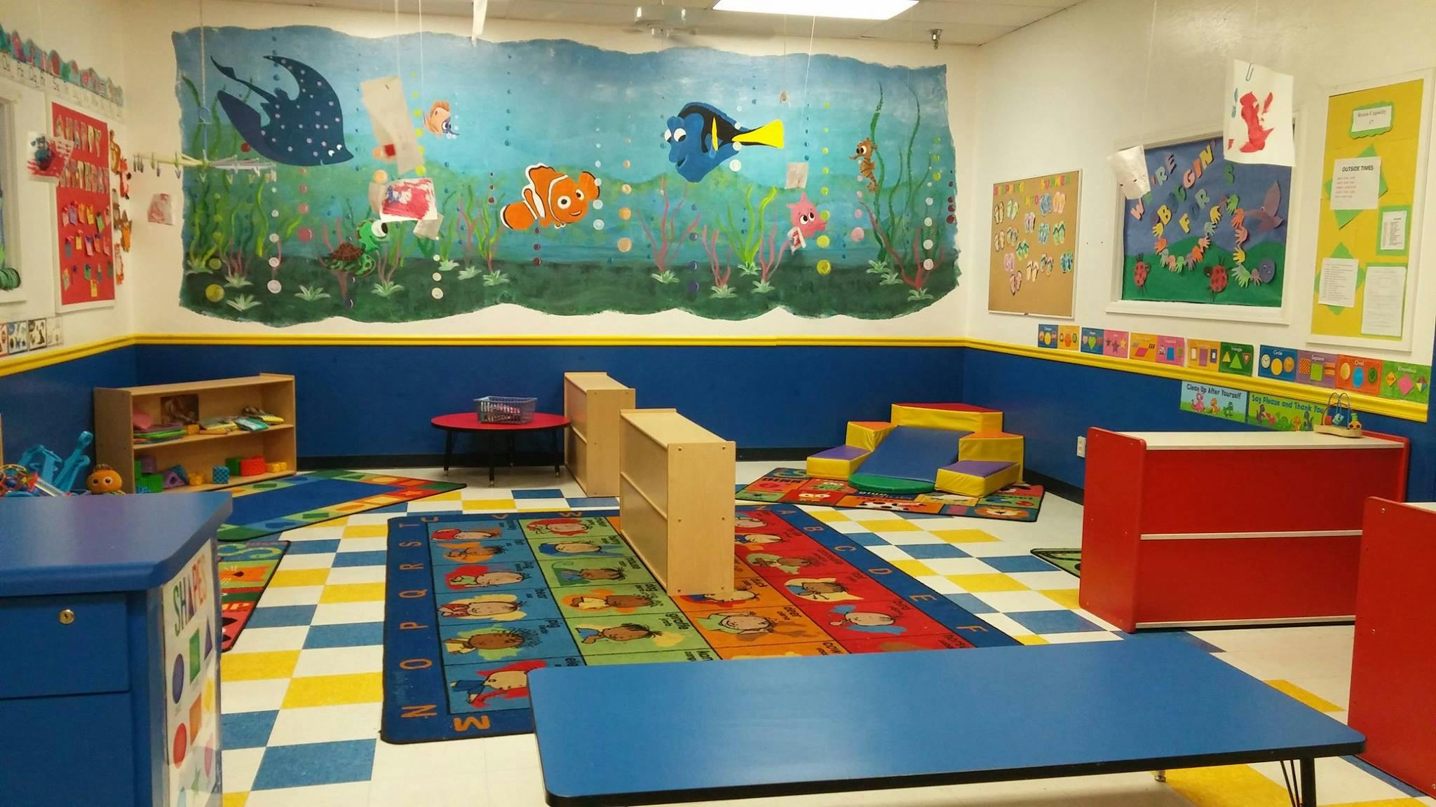 Classroom with colorful mural, blue walls, and play mats