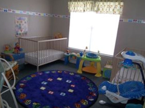 Nursery room with a crib, baby swing, and round blue rug