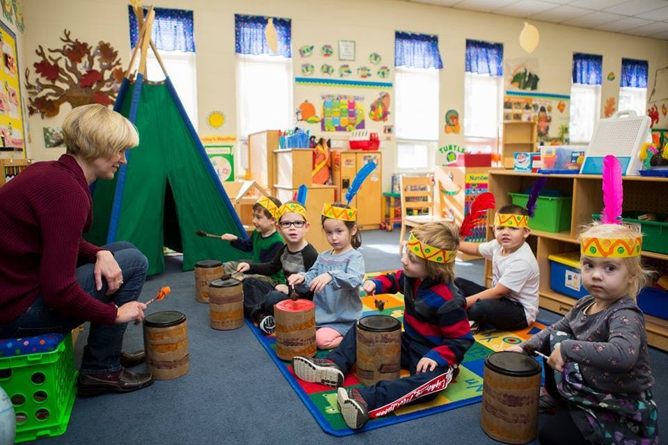 Adult and children playing drums in a classroom