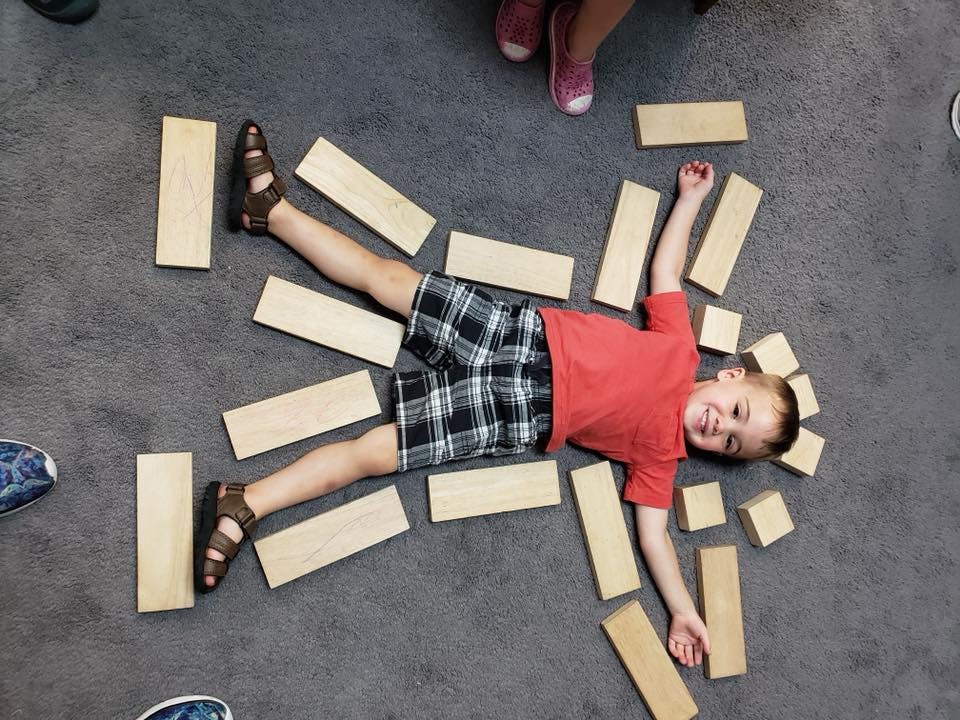 Child lying on floor surrounded by wooden blocks
