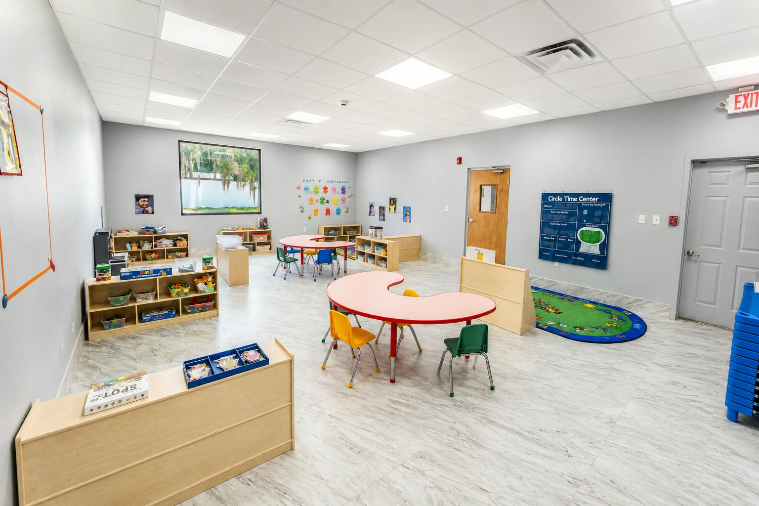 Spacious preschool classroom with tables and shelves for children