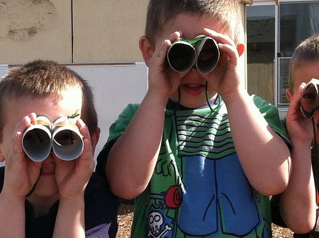 Children looking through cardboard tube binoculars
