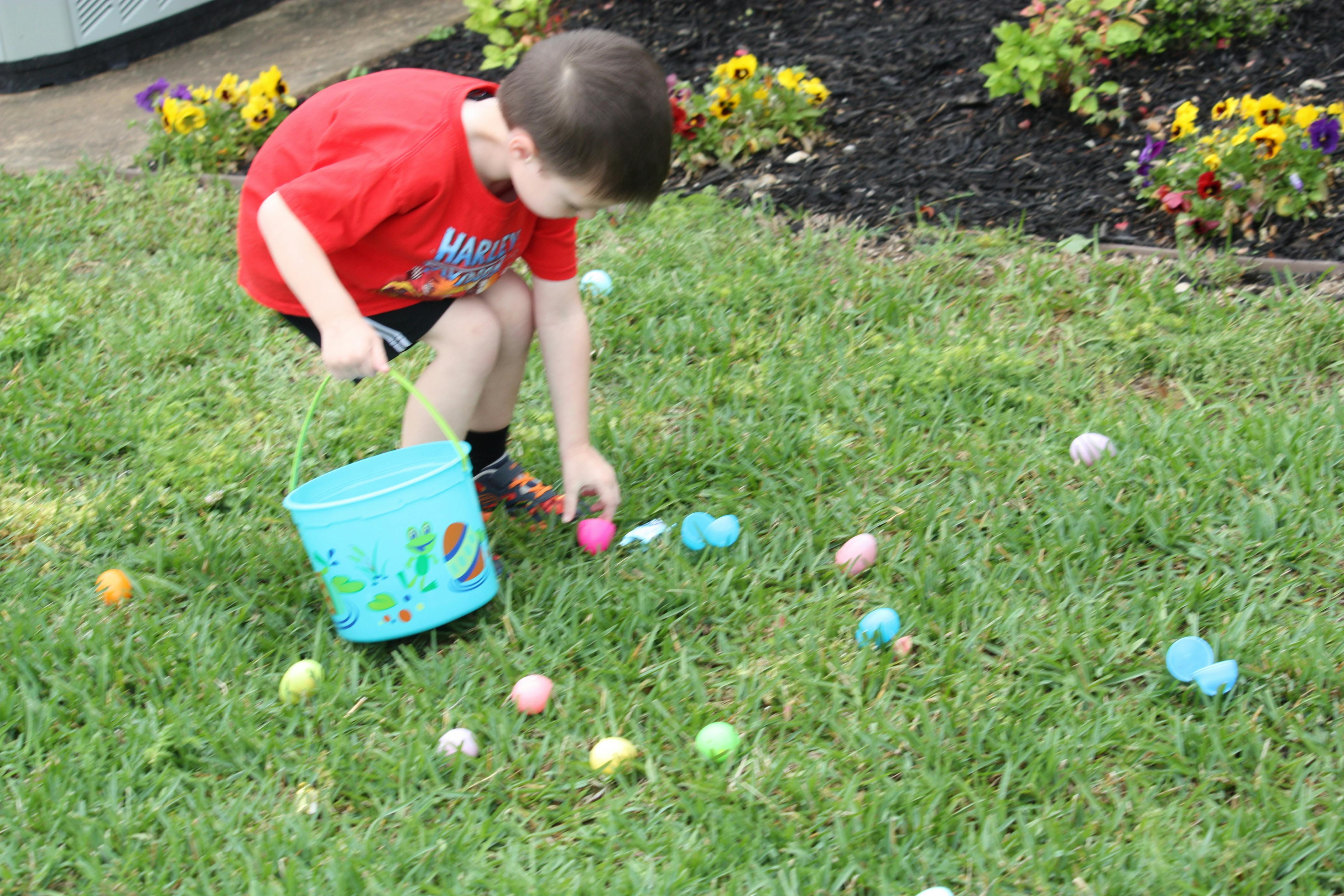 Child collecting plastic Easter eggs in a bucket on the grass