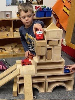 Child playing with wooden blocks and toy cars