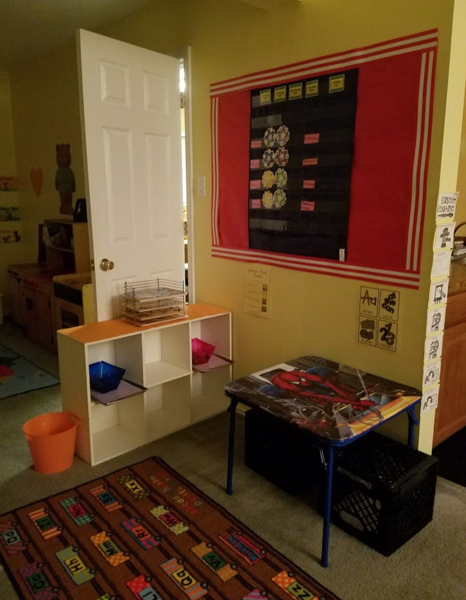 Classroom with a small table, storage unit, and a reward chart on the wall
