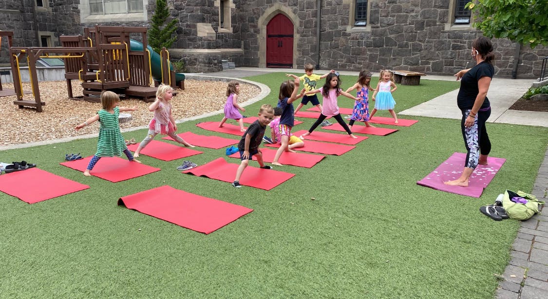 Adult leading children in outdoor yoga class