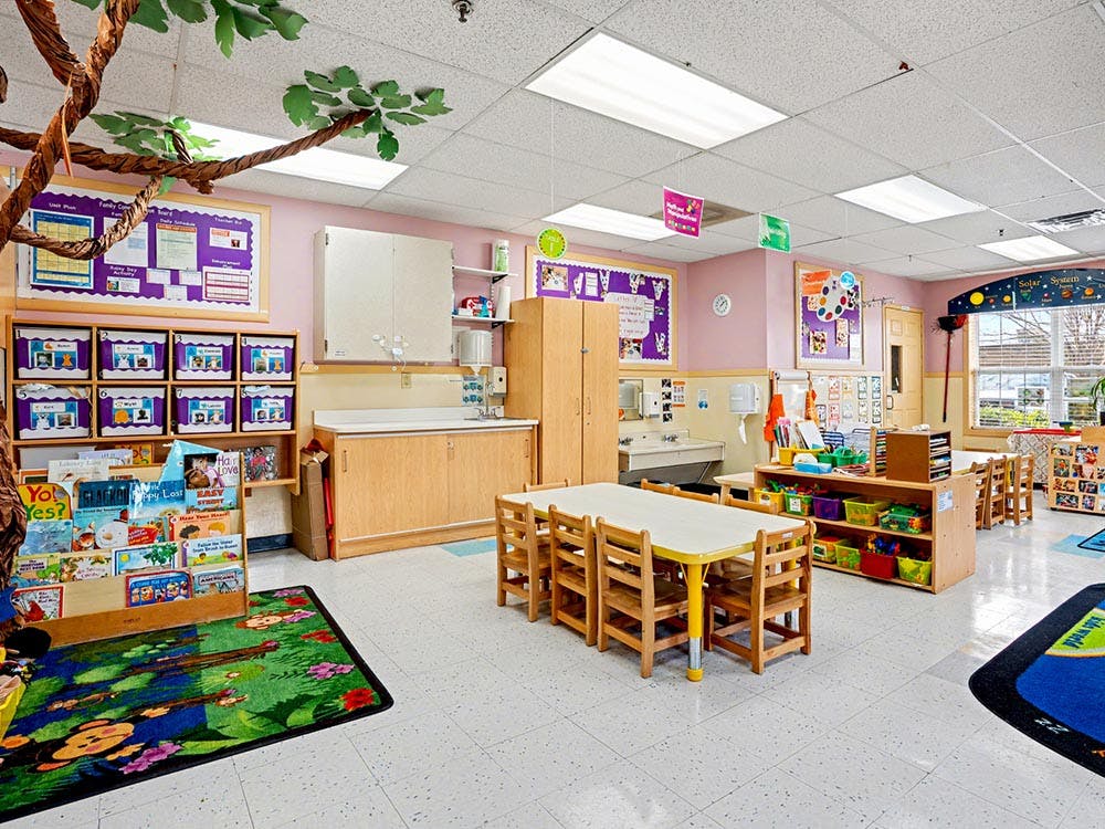 Colorful empty classroom with small tables and chairs