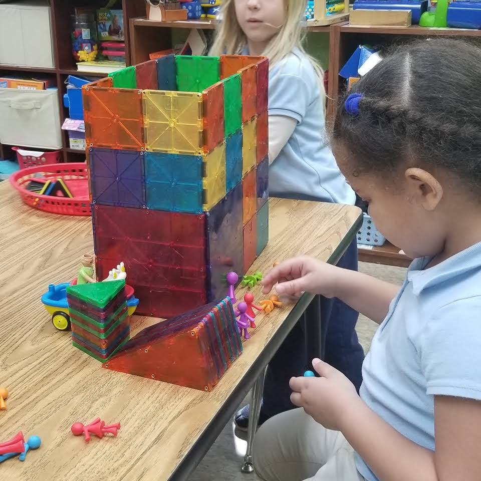 Child playing with colorful magnetic blocks and small figures on a table