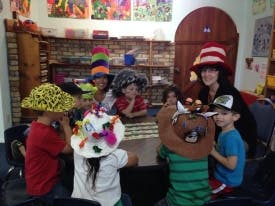Adult and children wearing decorative hats at a table