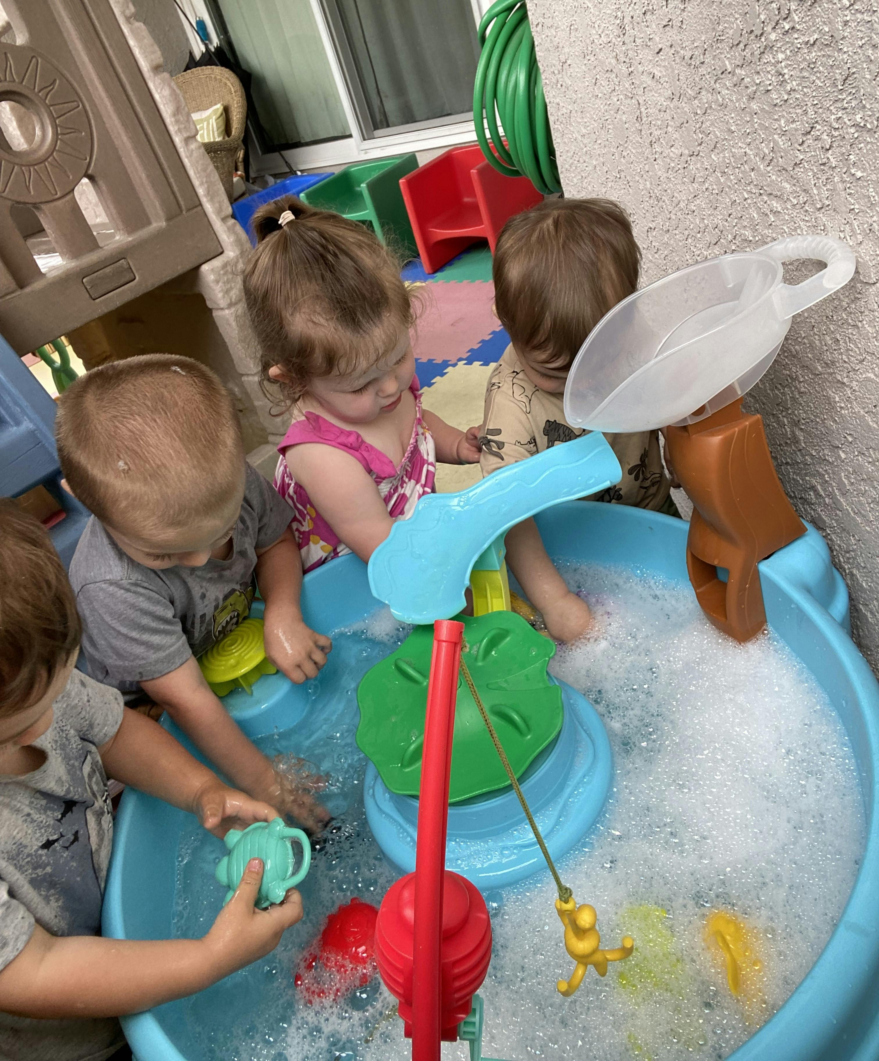 Three children playing with a water table