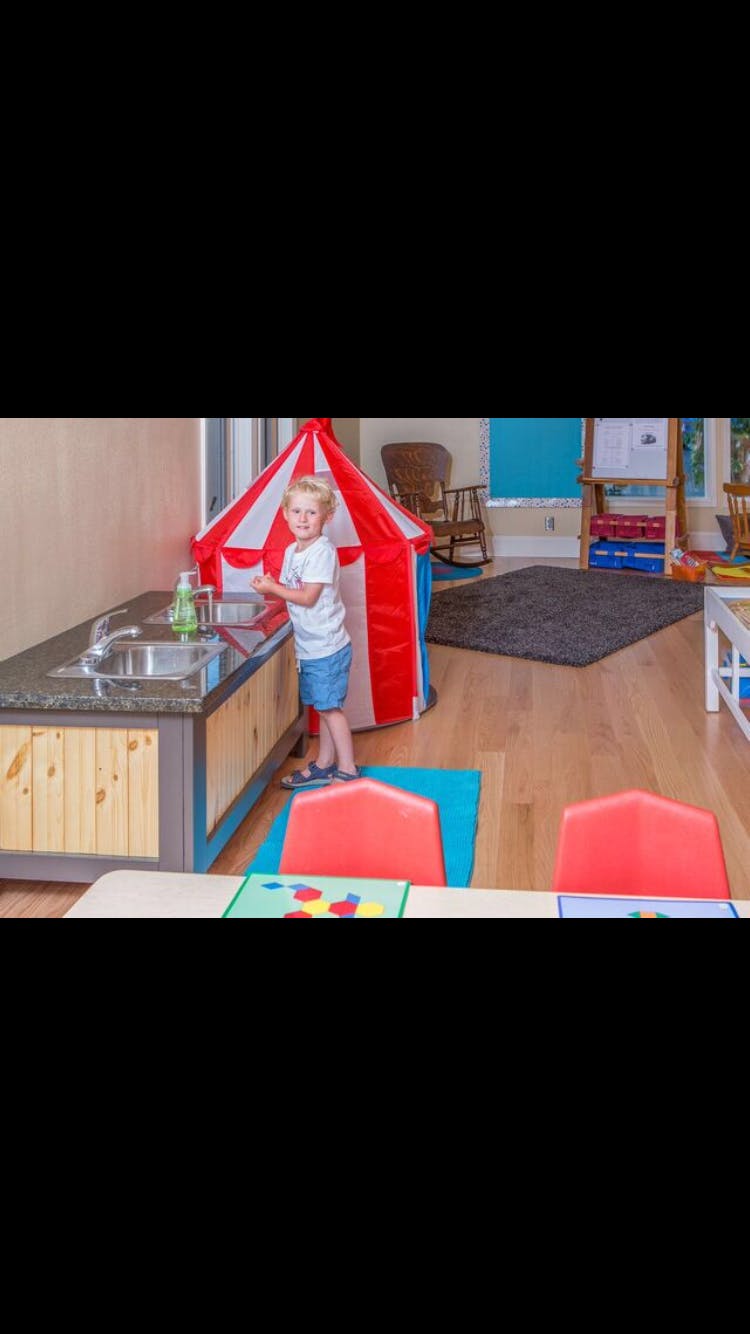 Child standing at a sink in a classroom