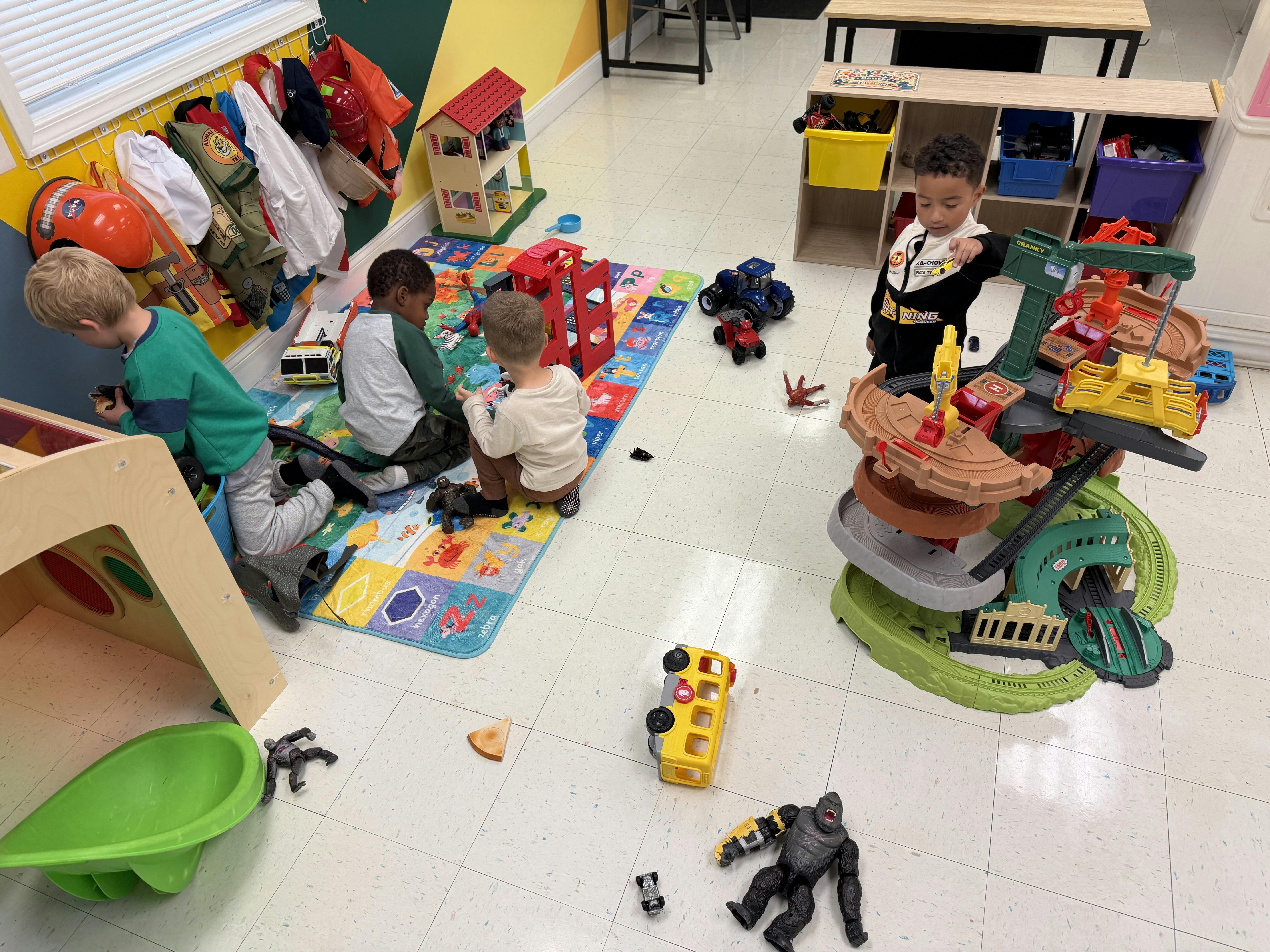 Children playing with various toys on a classroom floor