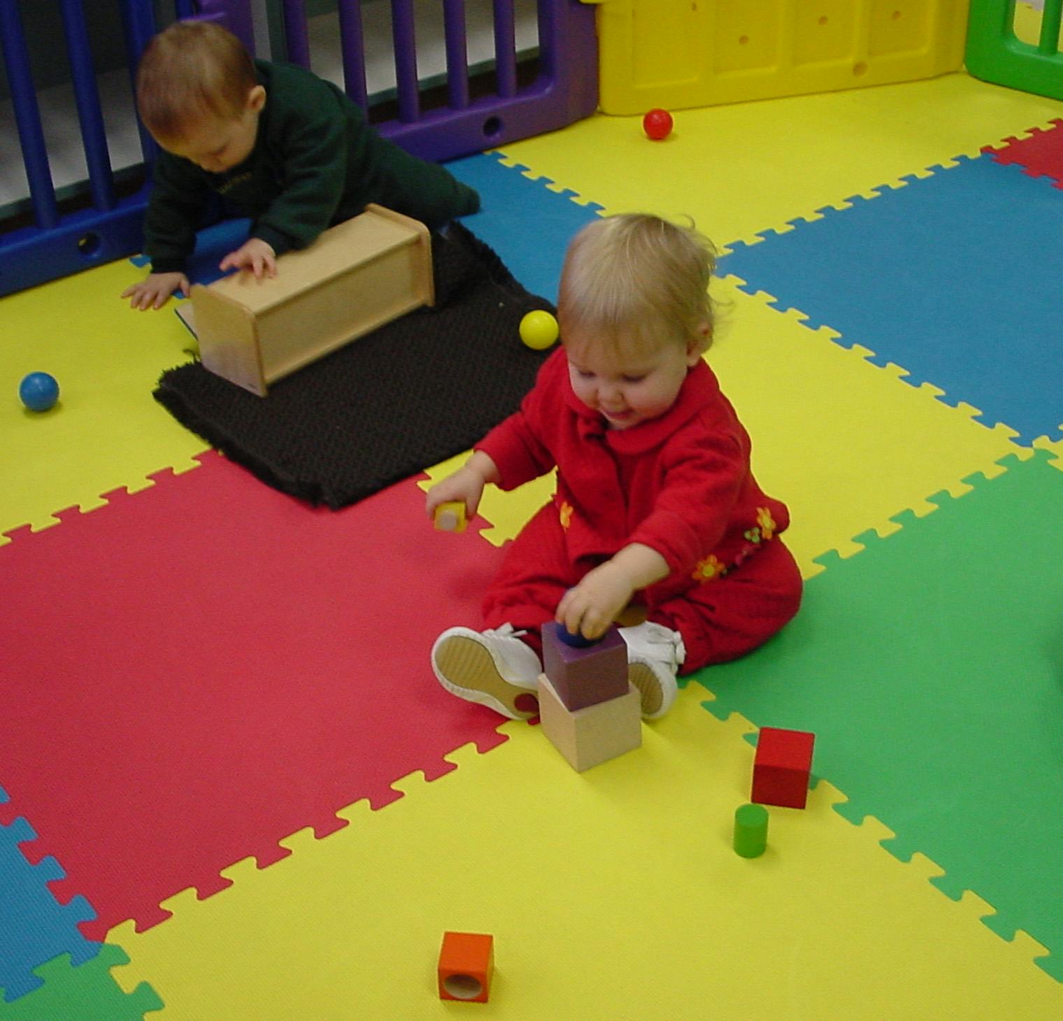 Two children playing with blocks on a colorful mat