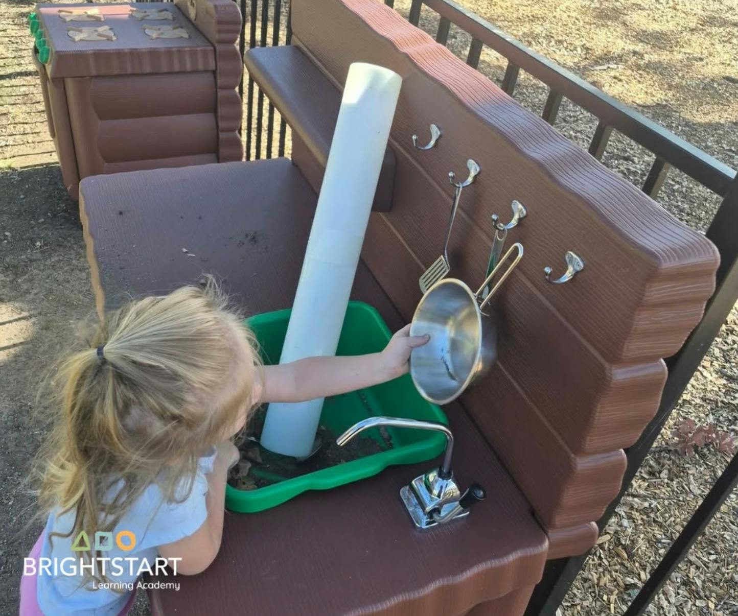 Child playing with a toy kitchen workstation outdoors