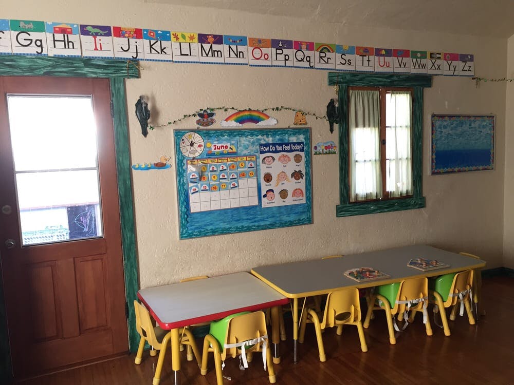 Classroom with small tables and chairs, alphabet banner, and bulletin board