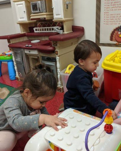 Two children playing with toys in a room with a play kitchen in the background