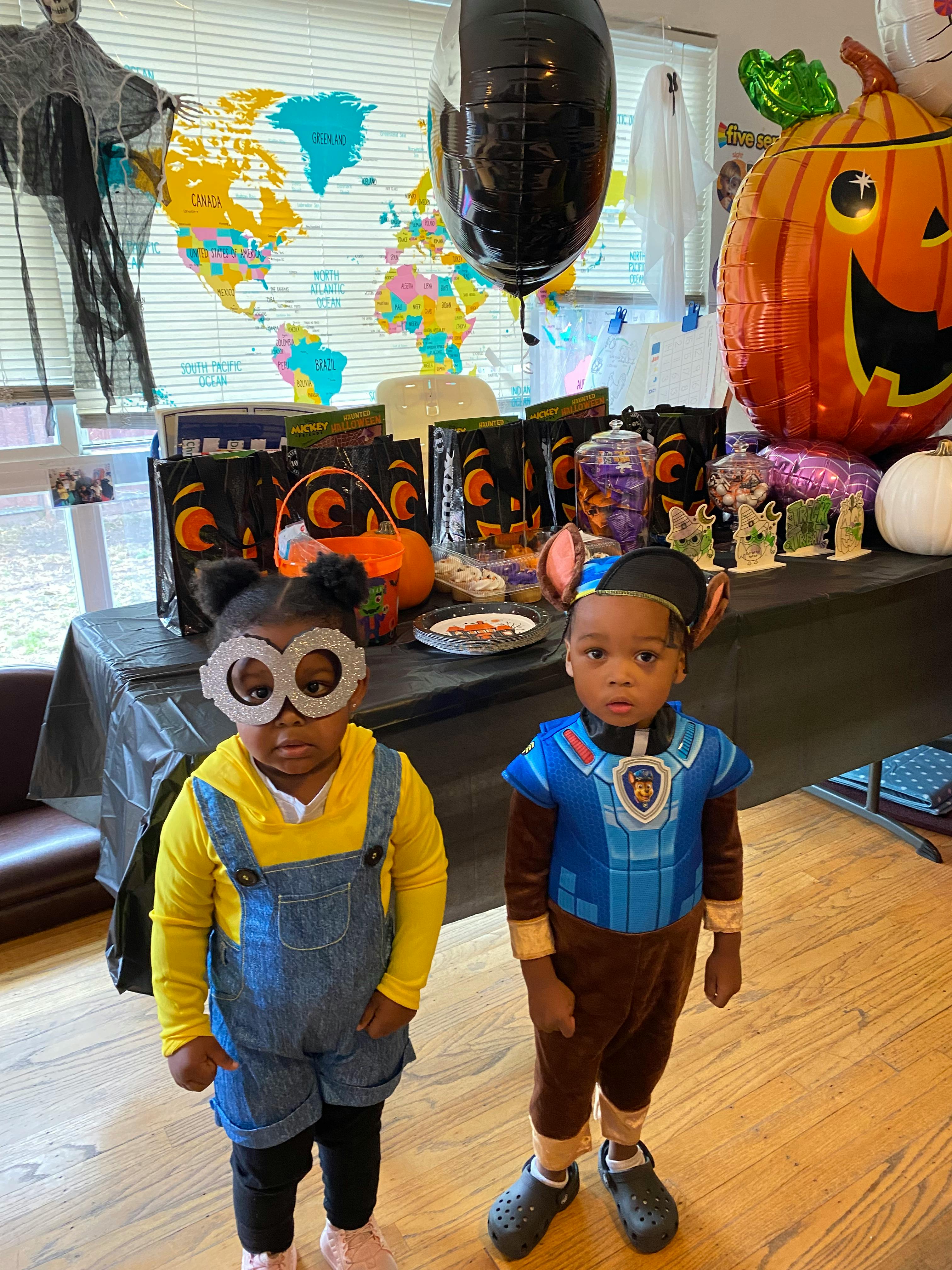 Two children in costumes standing in front of a decorated table