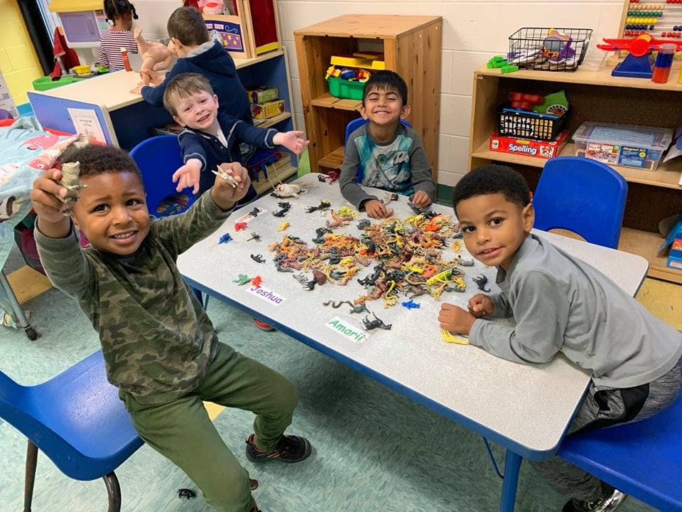 Children playing with toys at a table in a classroom