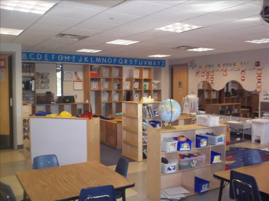 Classroom with tables, chairs, shelving units, and a globe