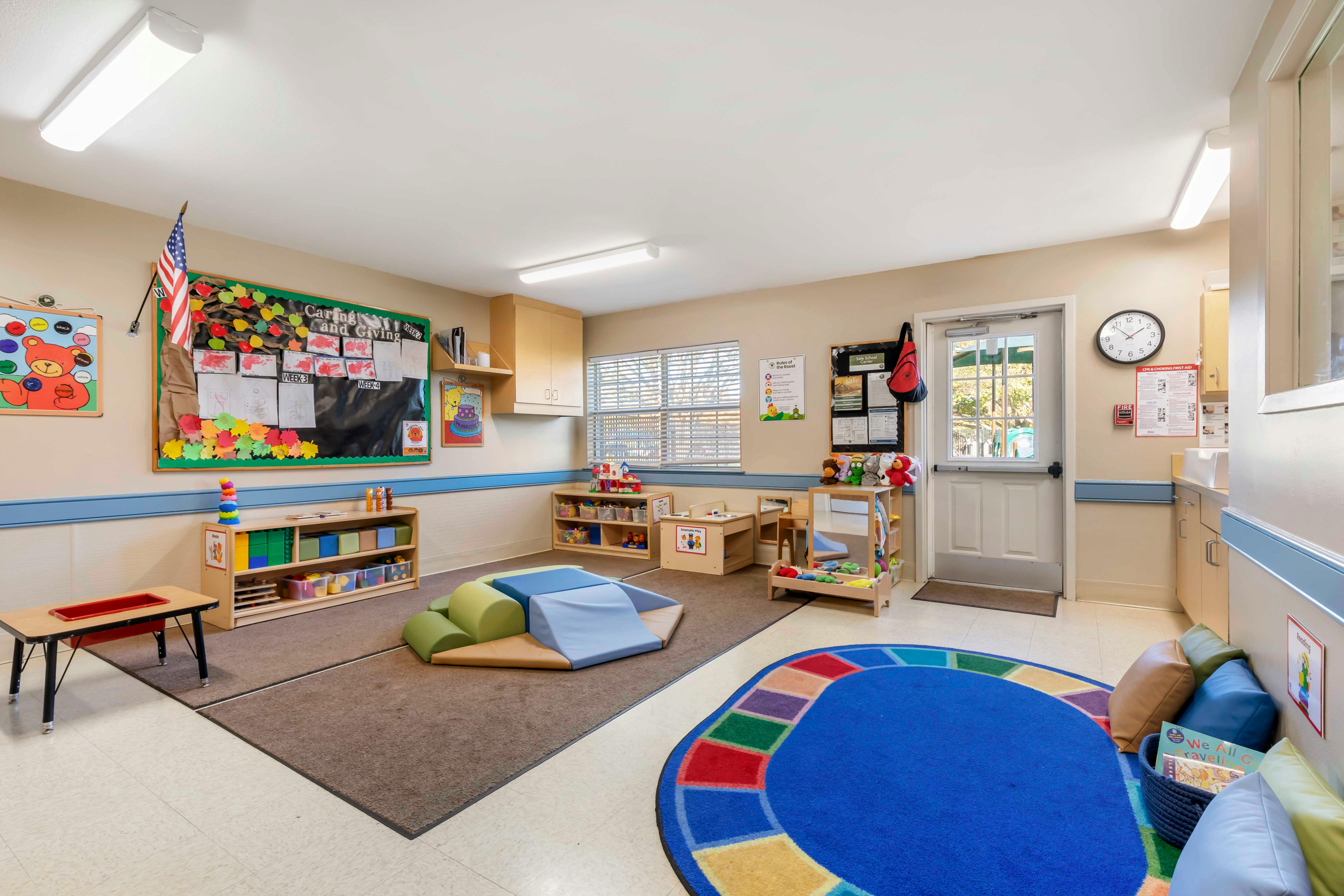 Classroom with play mats, toys, and a colorful rug