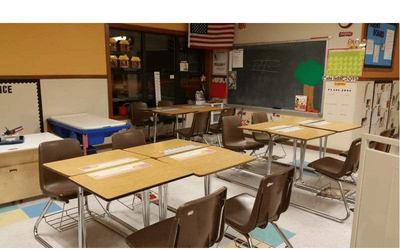 Classroom with empty student desks and chairs facing a chalkboard