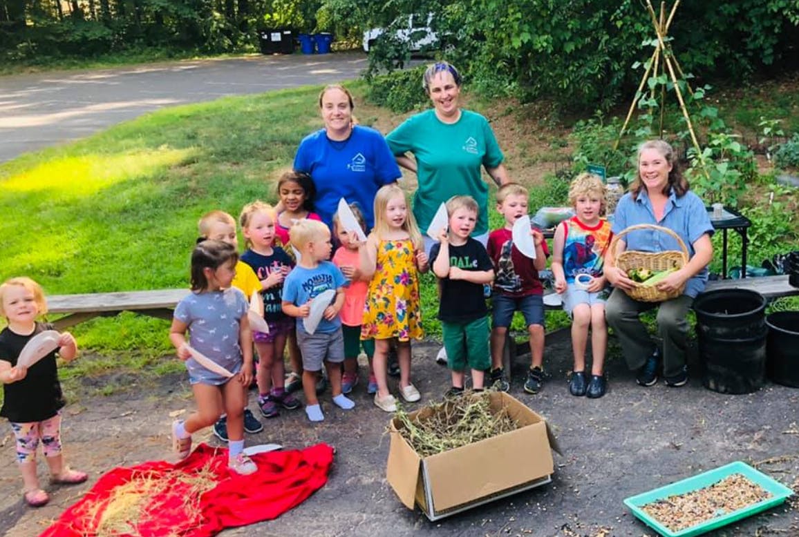 Adults and children gathered outdoors with gardening supplies