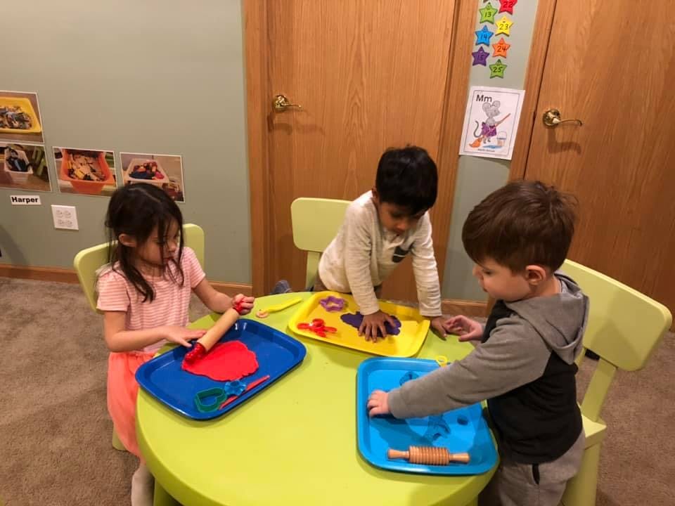 Three children playing with modeling clay at a table