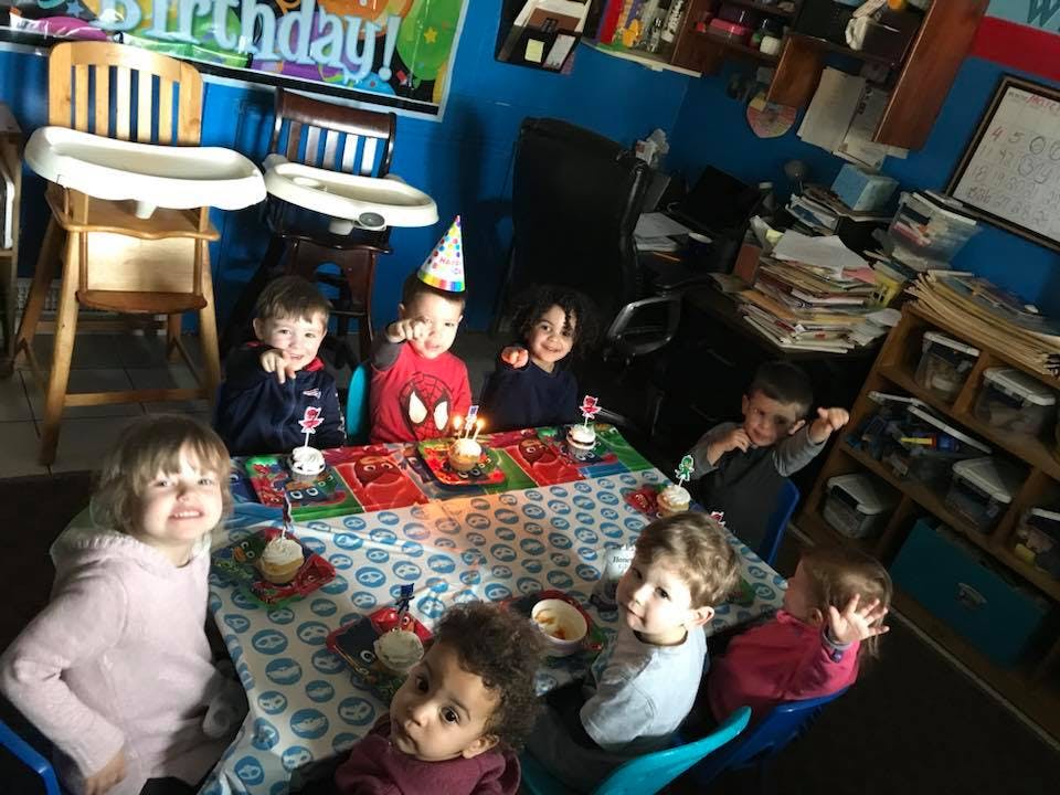 Children gathered around a table with a birthday cake