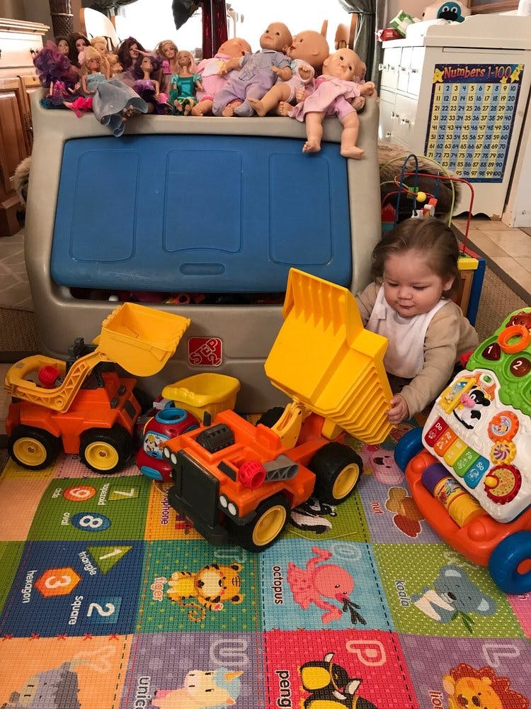 Child playing with toy construction trucks on a colorful mat