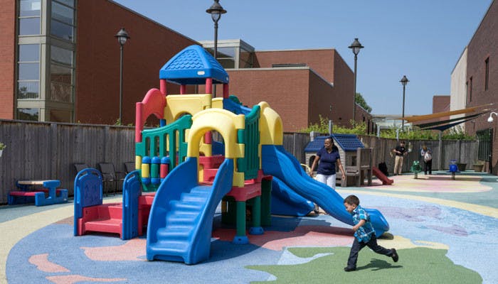 Child running on a playground with play structure