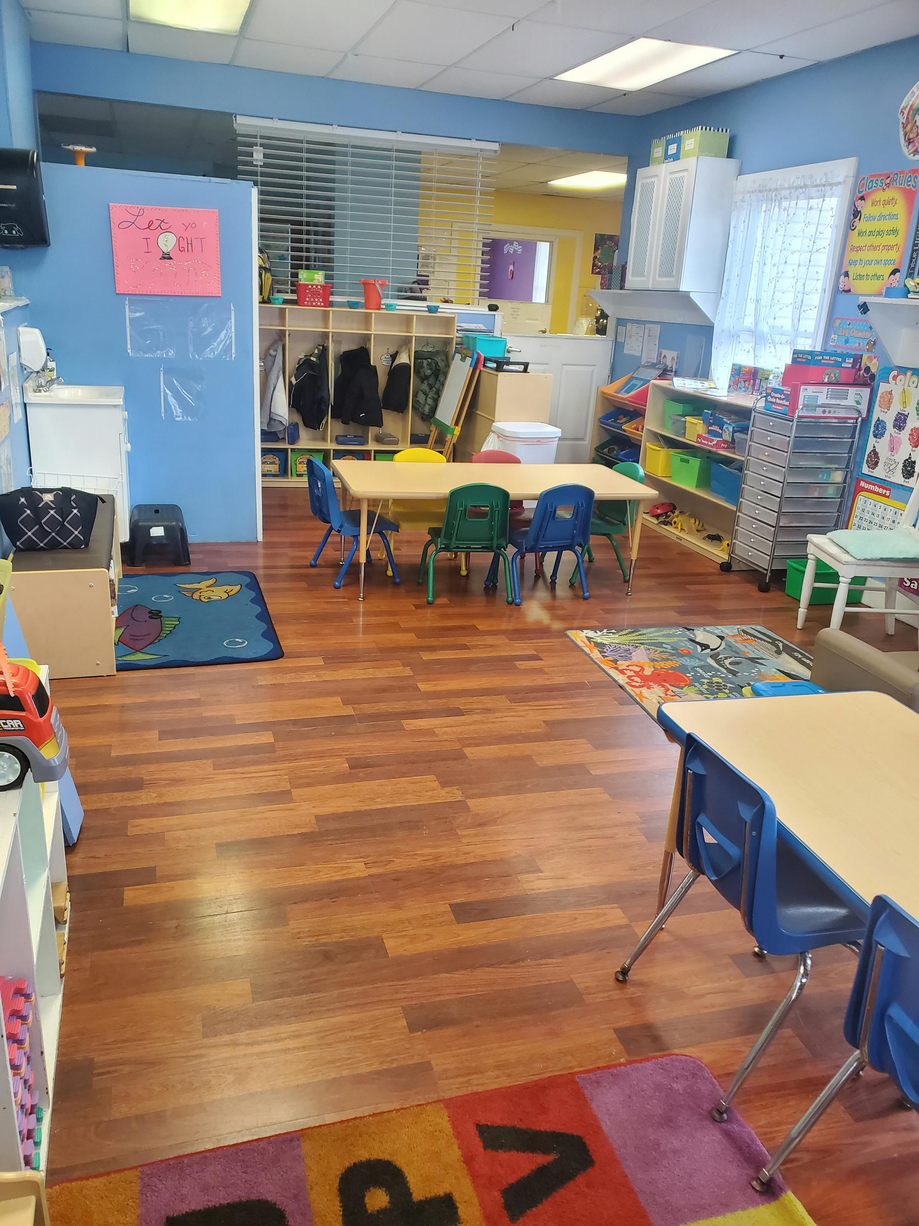 Classroom with small tables and chairs, cubbies, and colorful rugs
