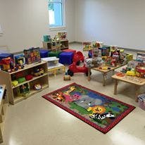 Playroom with toys, tables, and a colorful rug