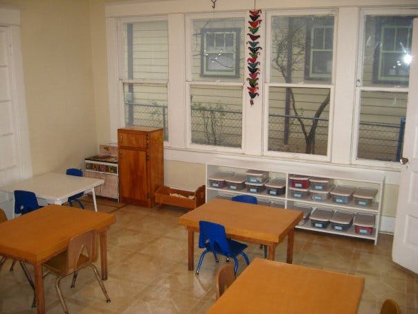 Classroom with small tables and chairs, storage shelves, and large windows