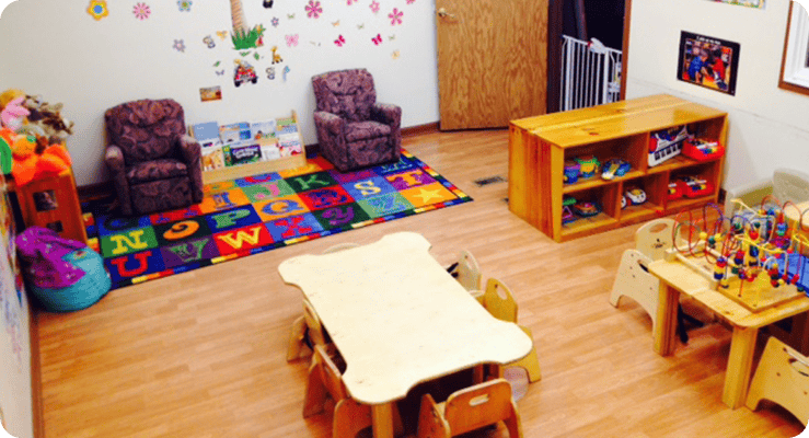 Playroom with small tables, chairs, and a colorful alphabet rug