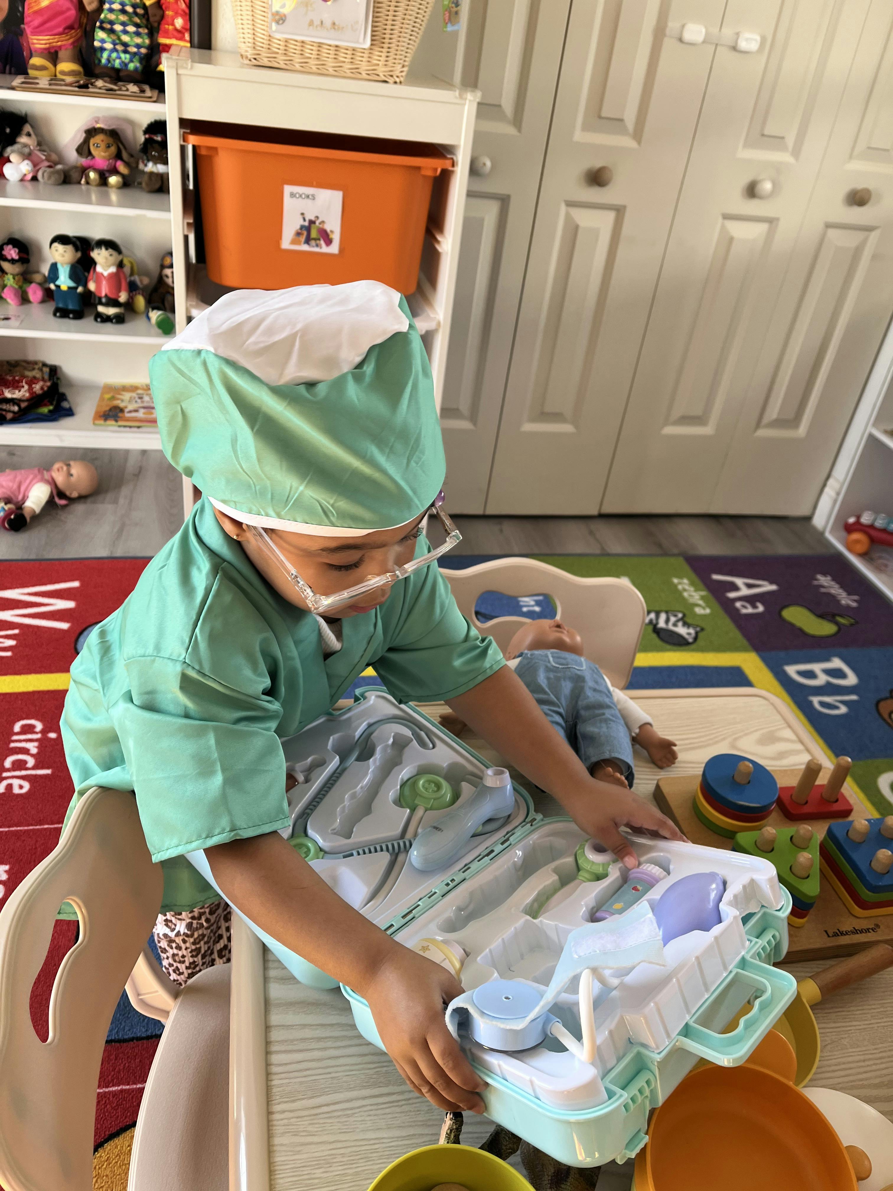 Child wearing surgical scrubs and glasses playing with a toy medical kit