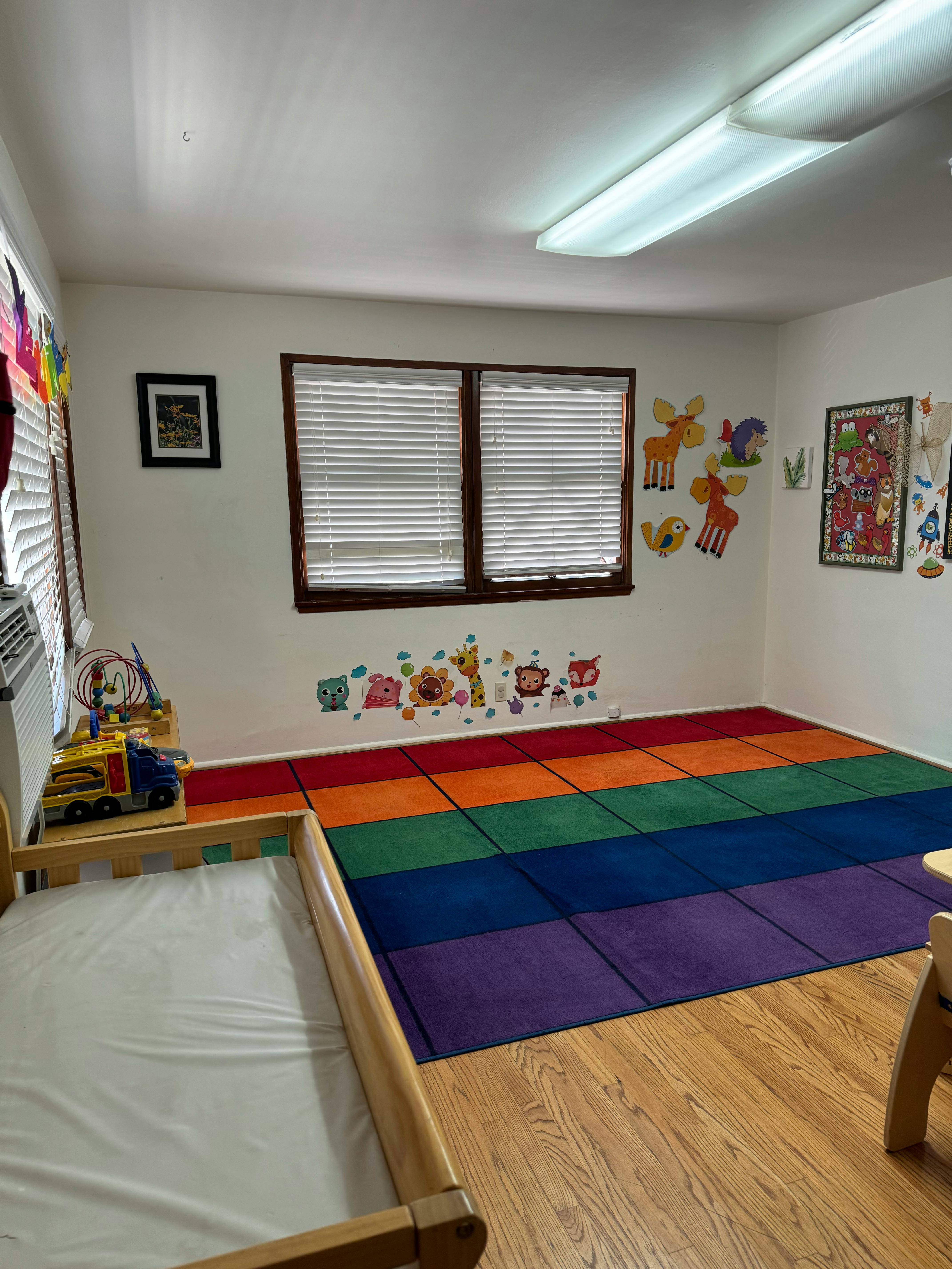 Child's room with a rainbow rug and a small bed
