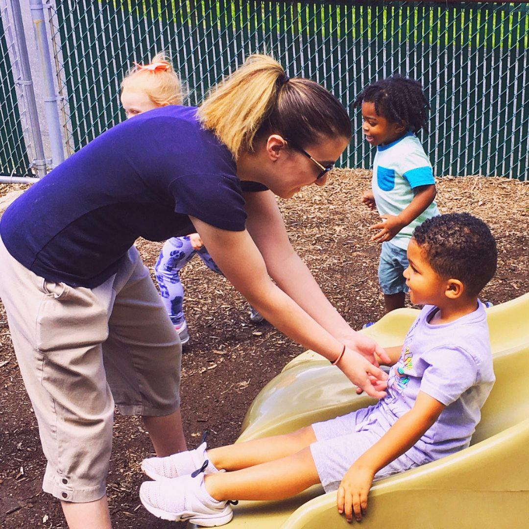 Person helping a child on a slide in a playground