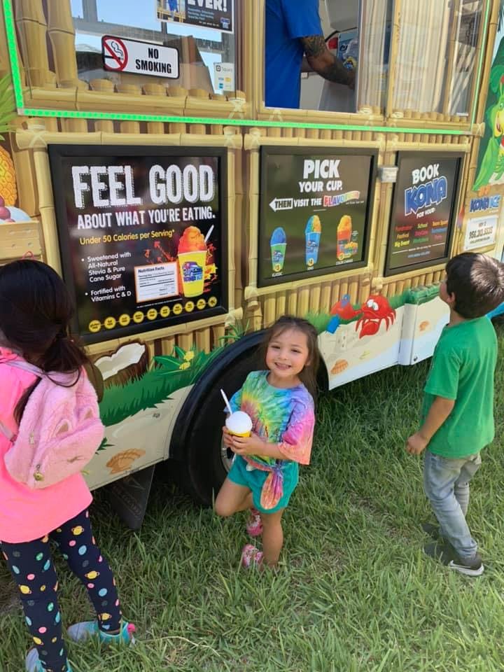 Children standing in front of a food truck, one child holding a cup