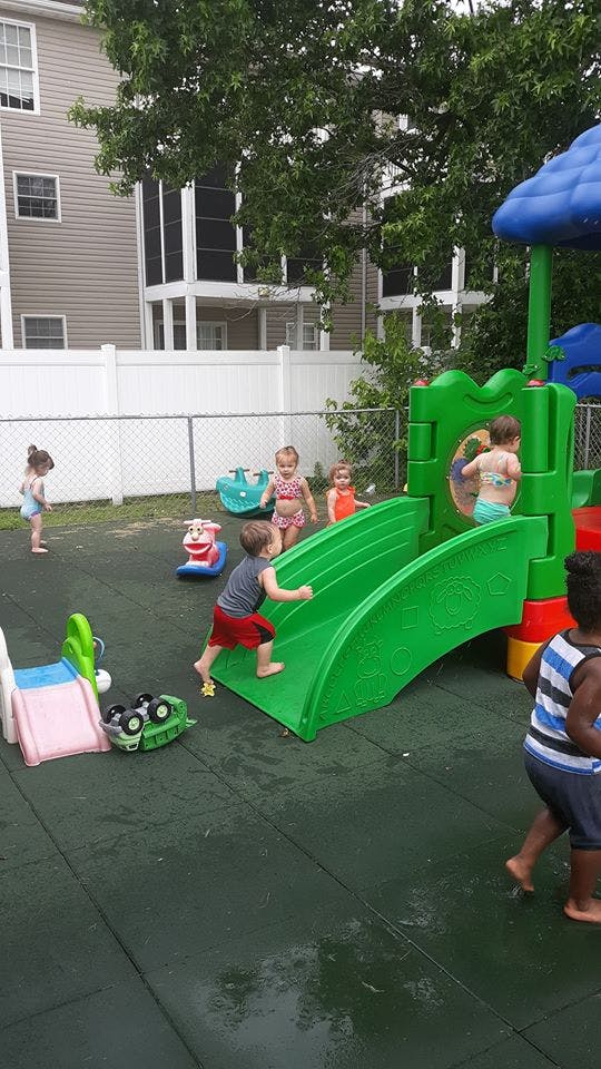 Children playing on a green slide and playground equipment