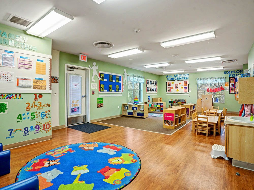 An empty early childhood classroom with small tables, chairs, and colorful decorations