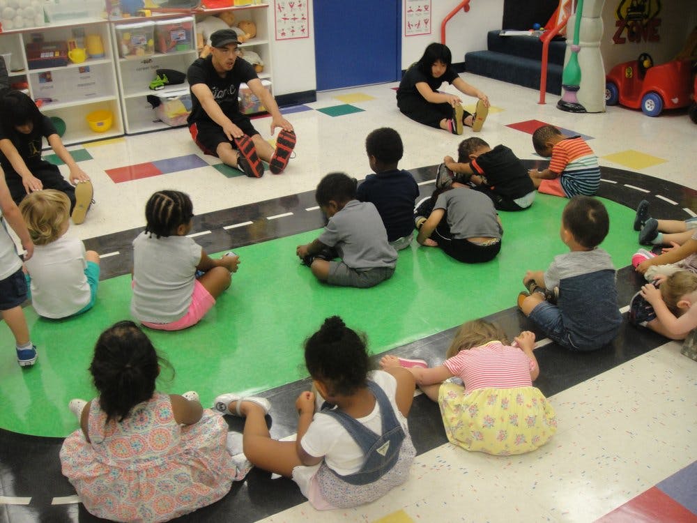 Adults and children sitting on the floor in a classroom