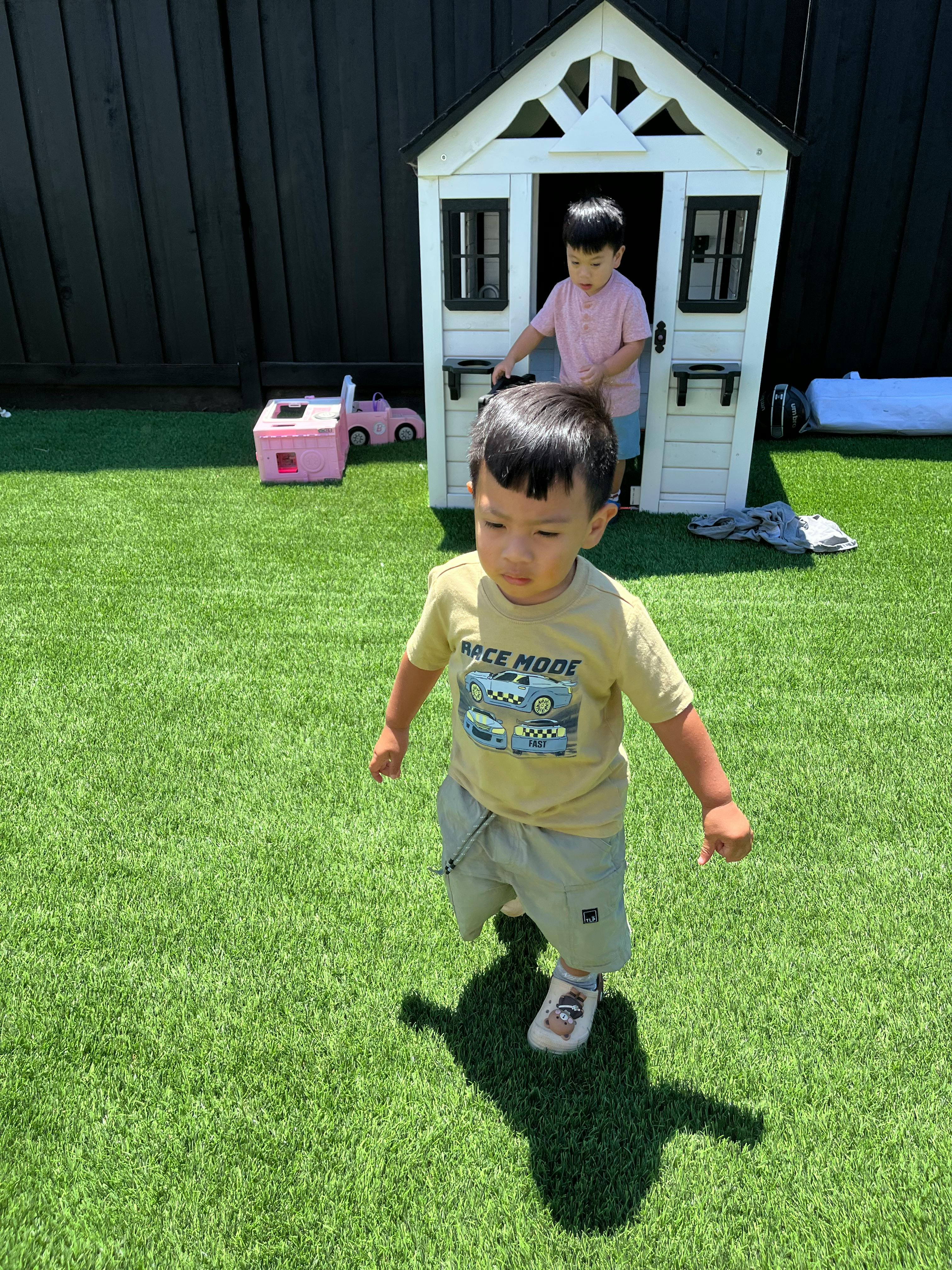 Child wearing a t-shirt with a race car graphic on artificial grass