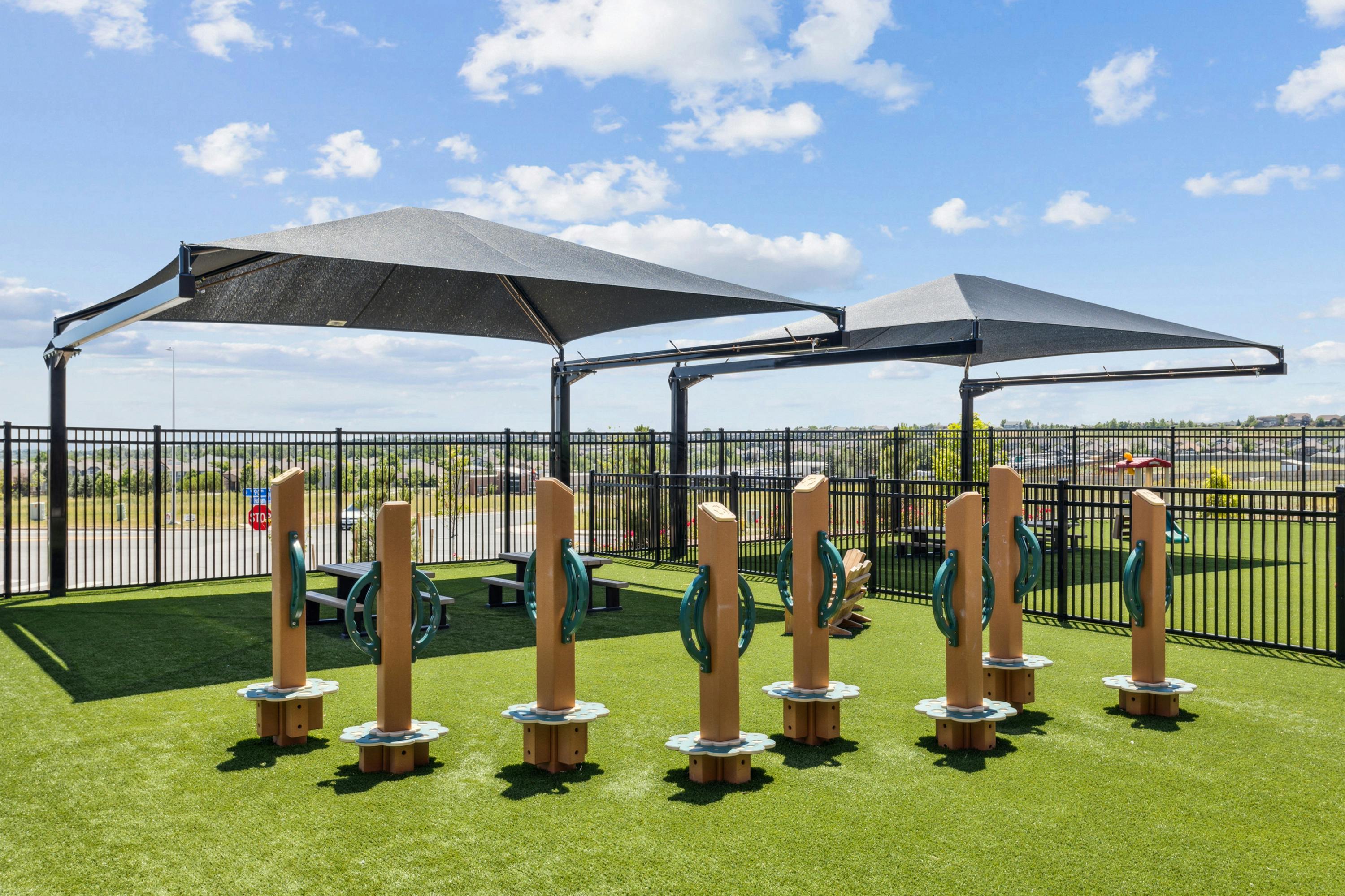 Outdoor play area with shade structures and wooden play equipment
