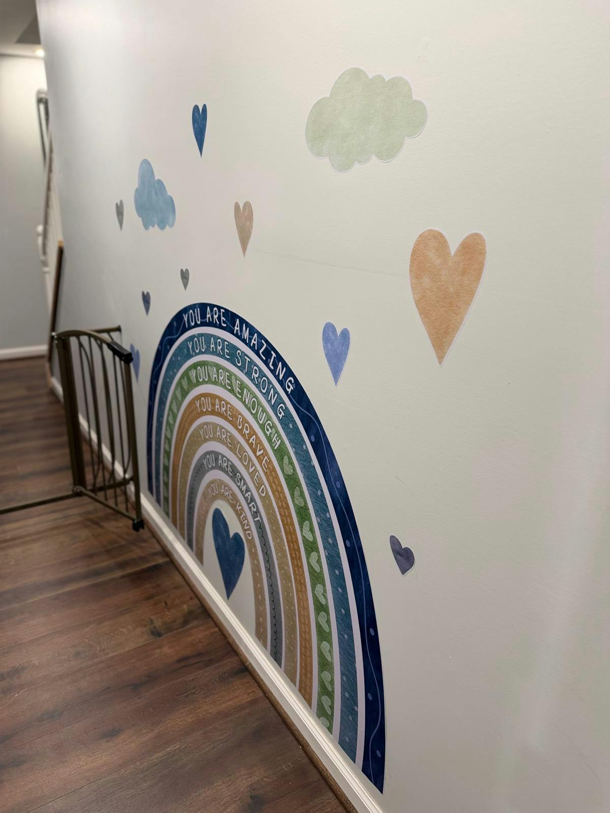 Wall decal of a rainbow with encouraging words and hearts, next to a baby gate