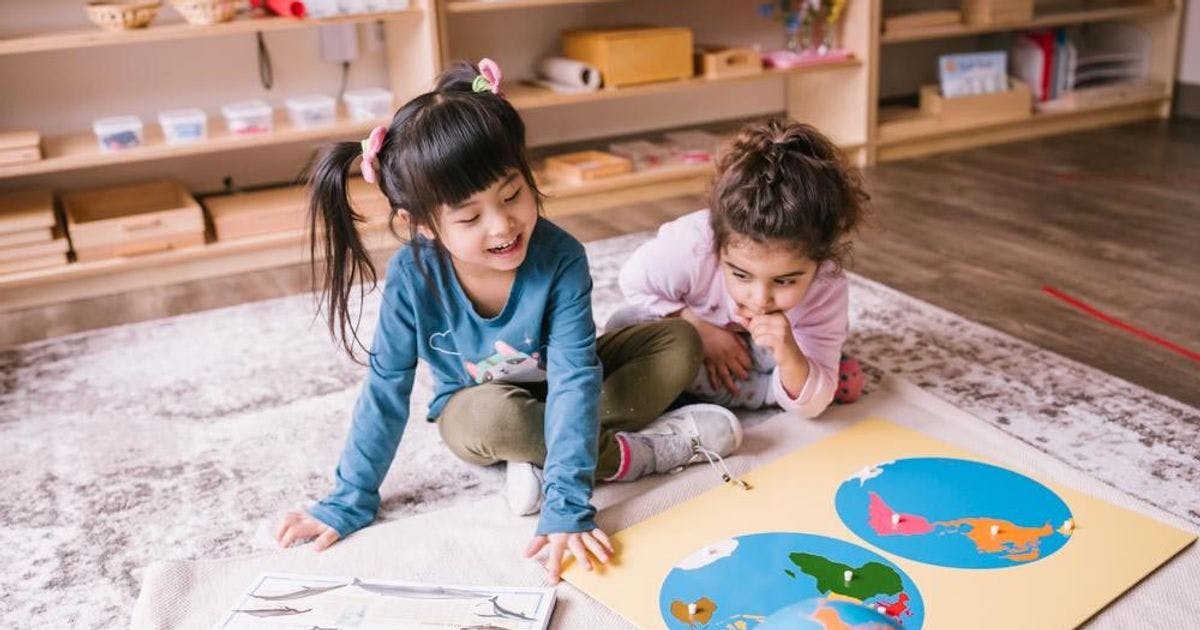 Two children sitting on a rug looking at a puzzle
