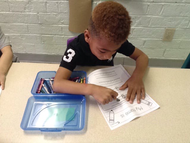Child coloring a paper at a desk