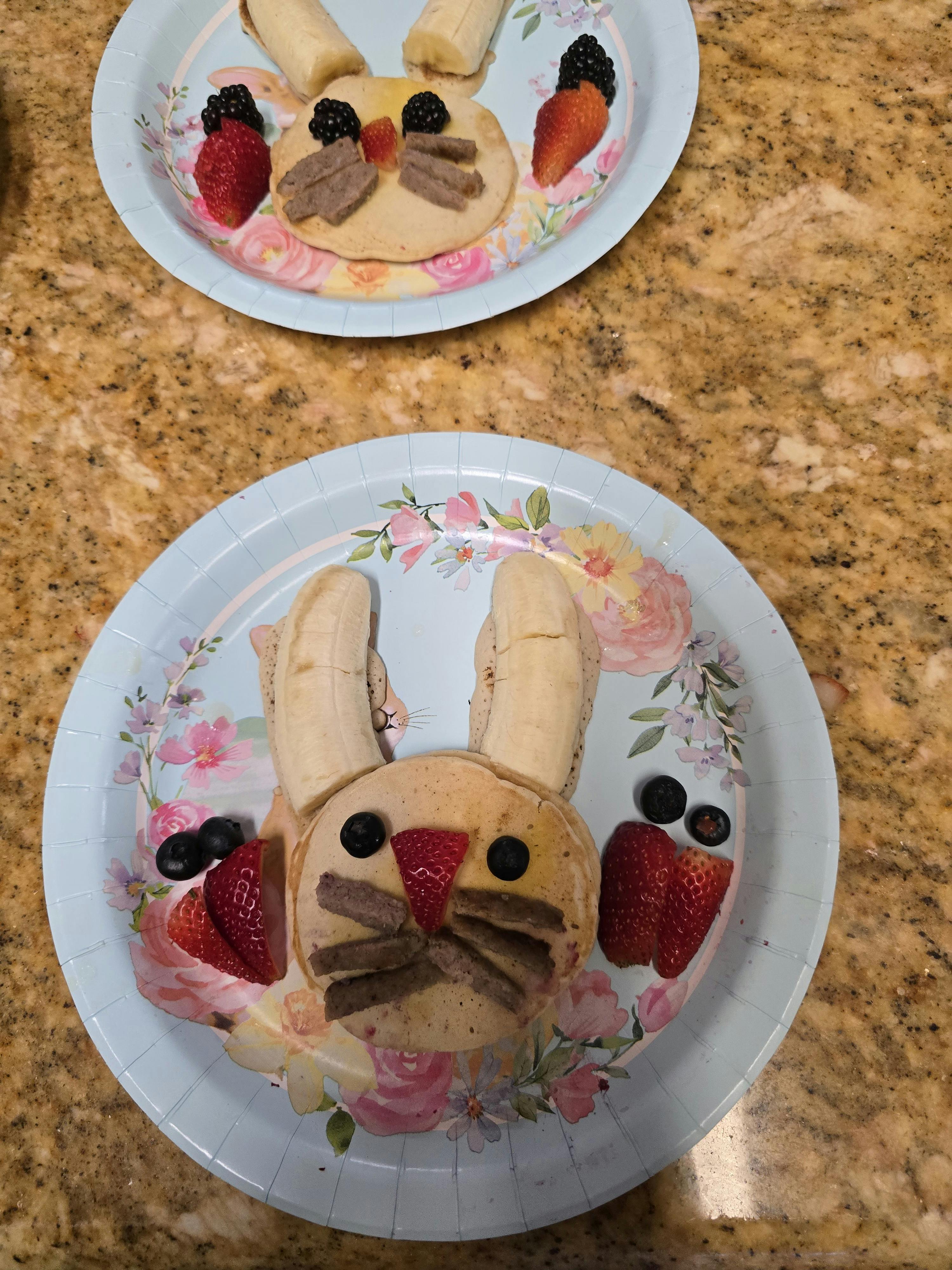 Pancakes decorated as bunny faces with fruit on plates